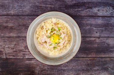 Geleneksel İtalyan makarna yemeği, yumurtalı spagetti carbonara, parmesan peyniri, siyah taştan arka planda pastırma, üst manzara. İtalyan yemeği ve makarna.