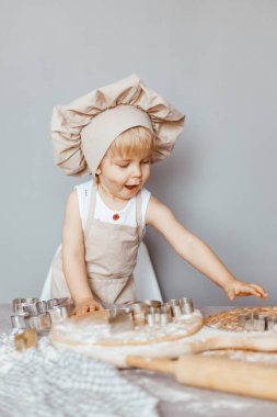 Önlük ve şef şapkasıyla hamur yoğuran küçük bir aşçının portresi. Çocuk yaşam tarzı konsepti pişirmek