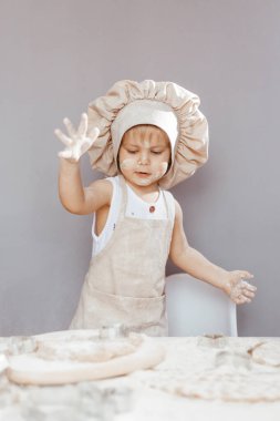 Önlük ve şef şapkasıyla hamur yoğuran küçük bir aşçının portresi. Çocuk yaşam tarzı konsepti pişirmek