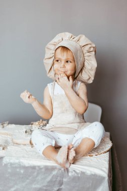 Önlük ve şef şapkasıyla hamur yoğuran küçük bir aşçının portresi. Çocuk yaşam tarzı konsepti pişirmek