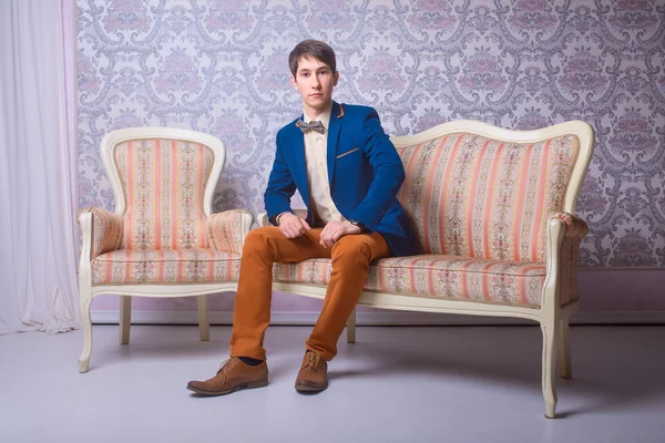 Young man in classic suit is sitting on the couch — Stock Photo, Image