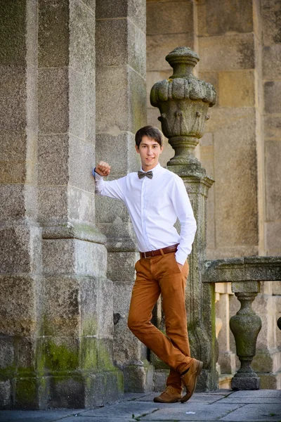 L'uomo alla moda in pantaloni beige costa su pareti di pietra — Foto Stock