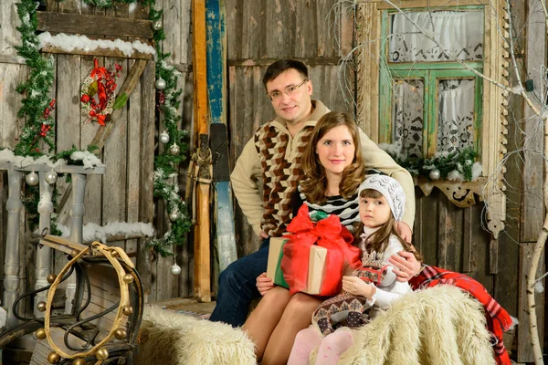 Дівчина з матір'ю і татом сидить на різдвяних санях — стокове фото