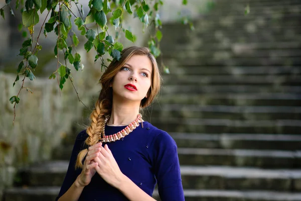 Menina posando em vestido azul de pé em escadas de pedra — Fotografia de Stock