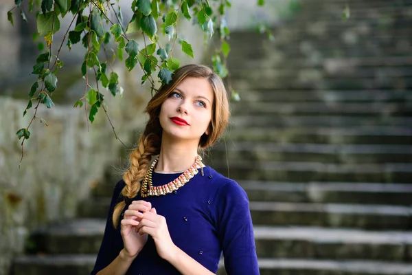 Flicka poserar i blå klänning stående på sten trappor — Stockfoto