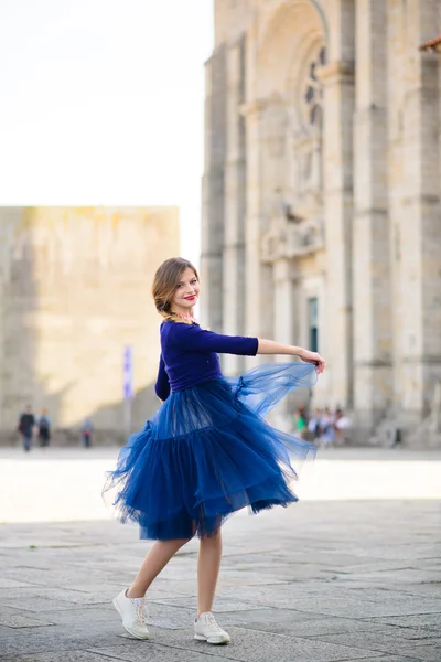 Jovem mulher elegante em azul vestido voador longo posando na escada contra o edifício da cidade velha — Fotografia de Stock