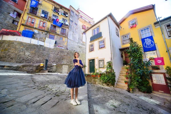A young girl stands on the street surrounded by the colourful houses in the port — Stock Photo, Image