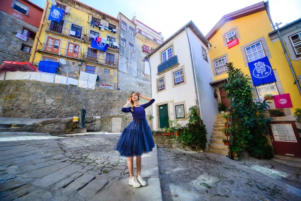 Молода дівчина стоїть на вулиці в оточенні барвистих будинків в порту — стокове фото