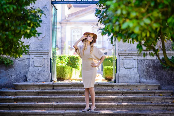 Mooie jonge vrouw met donker haar in elegante beige jurk die zich voordeed op de trap — Stockfoto