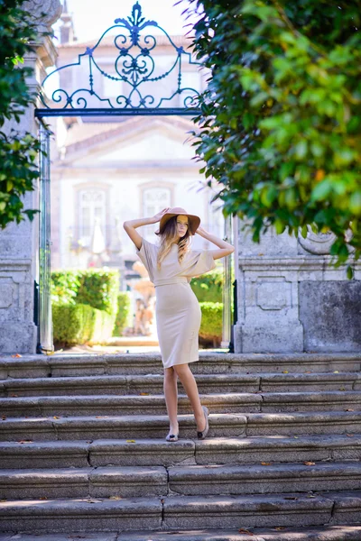 Bela jovem mulher com cabelo escuro em vestido bege elegante posando nas escadas — Fotografia de Stock