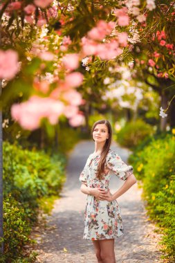 Genç kız çiçekli ağaç yakınındaki ayakta