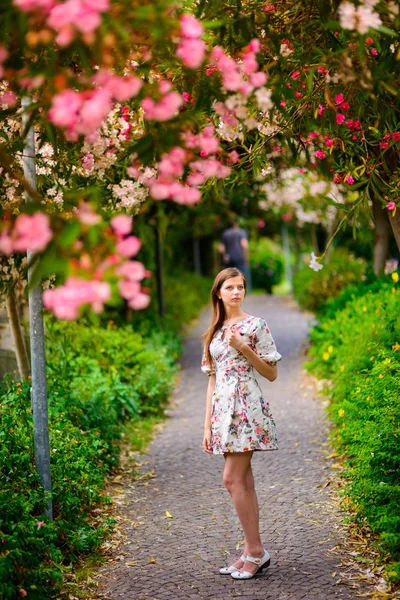 Giovane ragazza in piedi vicino albero con fiori — Foto Stock