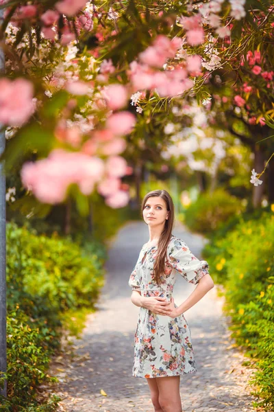 Ung flicka stående nära träd med blommor — Stockfoto
