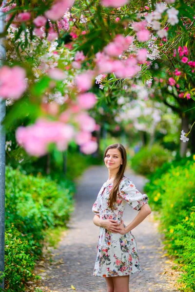 Giovane ragazza in piedi vicino albero con fiori — Foto Stock