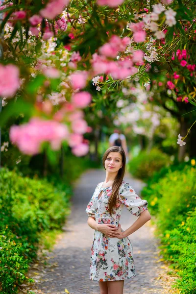 Giovane ragazza in piedi vicino albero con fiori — Foto Stock