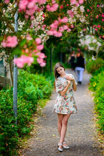 Giovane ragazza in piedi vicino albero con fiori — Foto Stock