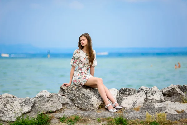 Schöne Frau sitzt auf einem Felsen über dem Meer — Stockfoto