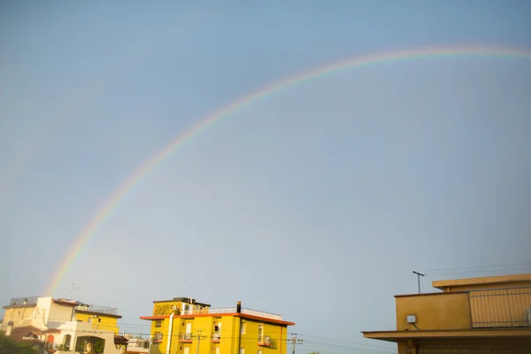 Rainbow at sunset under houses — Stock Photo, Image