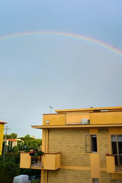 Regenboog bij zonsondergang onder huizen — Stockfoto