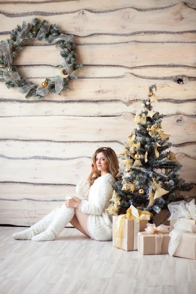 Bella ragazza in abito bianco seduta vicino a un bellissimo albero — Foto Stock