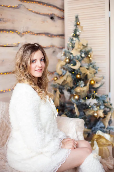 Schönes Mädchen in weißem Kleid, das neben einem schönen Baum sitzt — Stockfoto