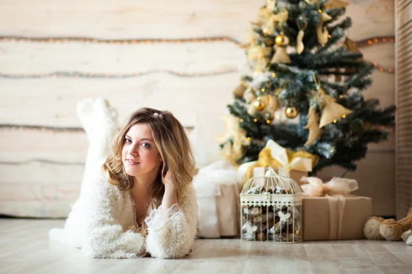 Bella ragazza in abito bianco seduta vicino a un bellissimo albero — Foto Stock