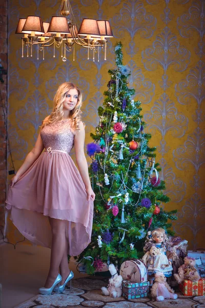 飾られたクリスマス ツリーの横に座っている女の子 — ストック写真