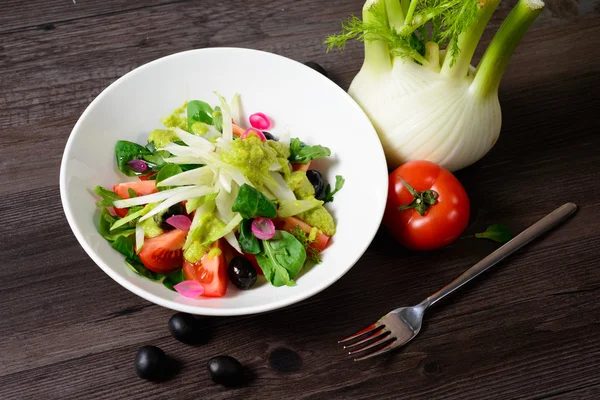 Salad on plate, next tomato and fork — Stock Photo, Image