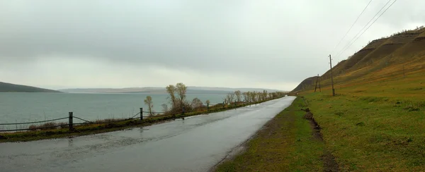 Strada desertica bagnata lungo il lago Fotografia Stock