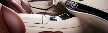 Modern lüks araba, direksiyon, vites kolu ve gösterge paneli. Araç içi lüks. Bej rahat koltuklar, direksiyon, gösterge paneli, hız göstergesi, ekran. Kırmızı ve beyaz delikli deri..