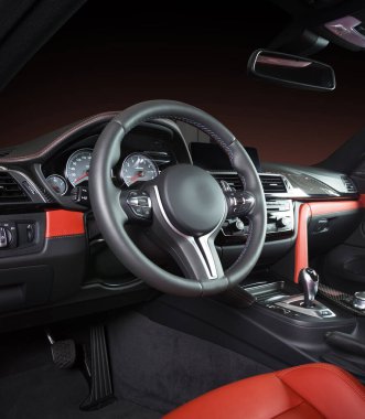 Modern lüks araba, direksiyon, vites kolu ve gösterge paneli. Arabanın içi lüks. Direksiyon, torpido, hız göstergesi, ekran. Kırmızı ve siyah deri kokpit