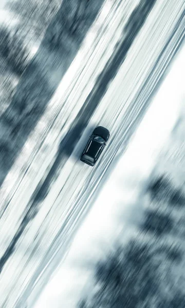 Aerial view of a car on winter road. Winter landscape countryside. Aerial photography of snow forest with a car on the road. Captured from above with a drone. Aerial photo. Quadcopter. Aerial car view. Motion blur effect