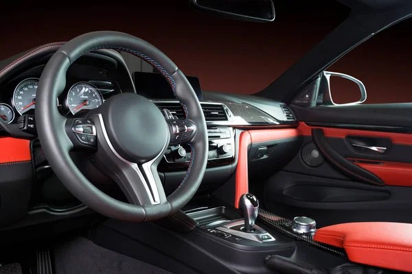 Modern luxury car Interior - steering wheel, shift lever and dashboard. Car interior luxury inside. Steering wheel, dashboard, speedometer, display. Red and black leather cockpit