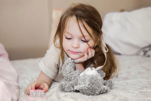 Liten flicka i sängen spelar — Stockfoto