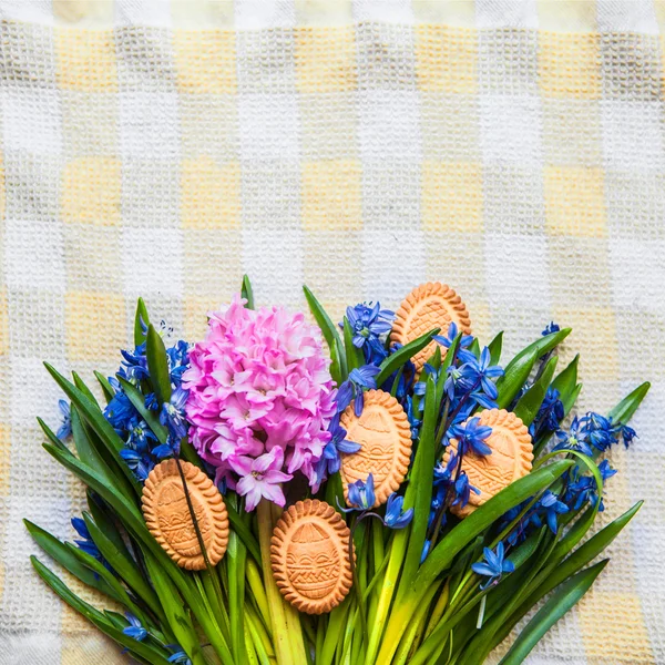 Top view of cookies in the shape of Easter eggs lie on scilla colors on yellow kitchen towel Stock Photo