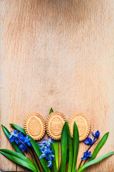 Top view of cookies in the shape of Easter eggs and Scilla lie on a wooden cutting board Royalty Free Stock Photos