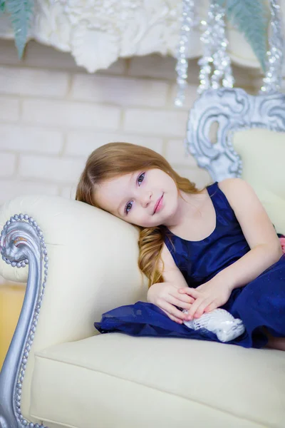 Menina em um vestido elegante sentado junto à lareira — Fotografia de Stock