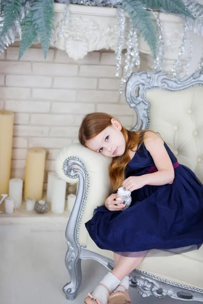 Kleines Mädchen in elegantem Kleid, das auf einem Stuhl sitzt und in die Kamera blickt — Stockfoto