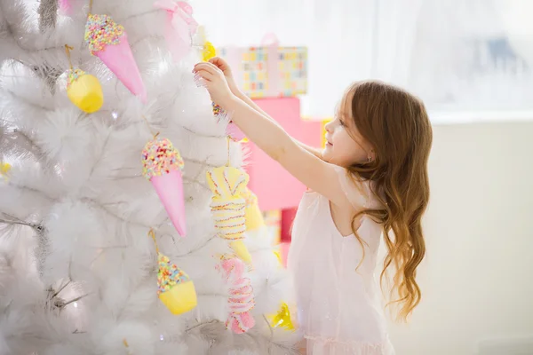 Μικρό κορίτσι σε ένα κομψό φόρεμα στολίζουν το χριστουγεννιάτικο δέντρο — Φωτογραφία Αρχείου