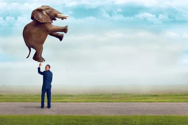 Businessman holding an elephant with one finger — Stock Photo, Image