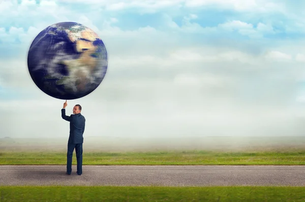 Empresário segurando planeta terra com um dedo — Fotografia de Stock