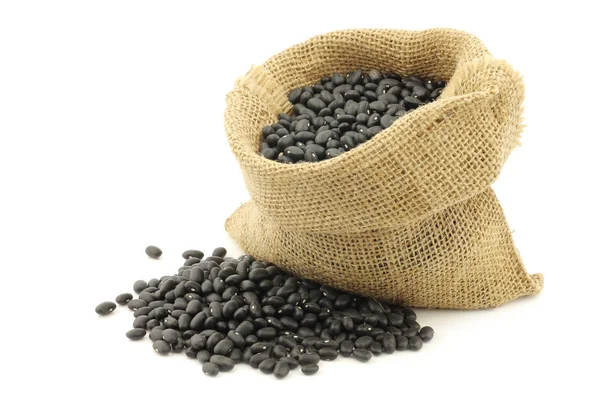 Feijão preto seco em um saco de serapilheira — Fotografia de Stock