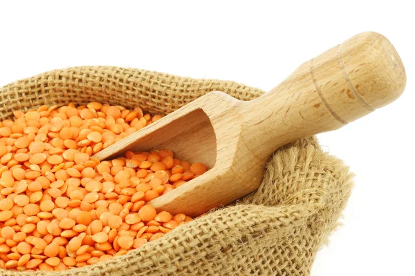 Red lentils in a burlap bag with a wooden scoop — Stock Photo, Image