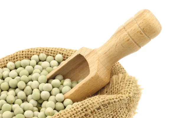 Green peas in a burlap bag with a wooden scoop — Stock Photo, Image