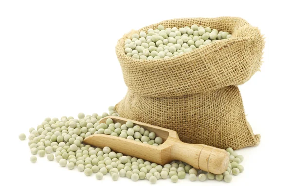Green peas in a burlap bag with a wooden scoop — Stock Photo, Image