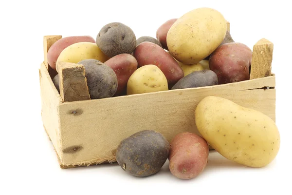 Papas amarillas, rojas y moradas en una caja de madera — Foto de Stock