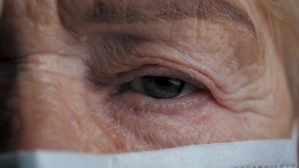 Close-up van droevig oog van zieke oude vrouw op isolatie van coronavirus thuis — Stockvideo