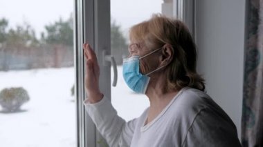 Koruyucu Yüz Maskeli Yaşlı Kadın Pencere önünde elini sallıyor