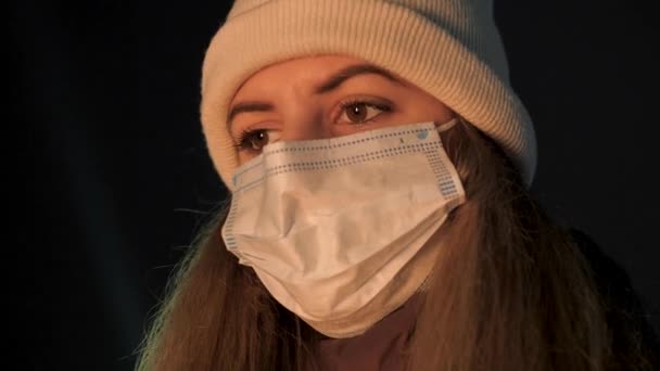 Mujer con máscara antiviral en su cara mirando con suerte al fuego en la noche de invierno — Vídeos de Stock