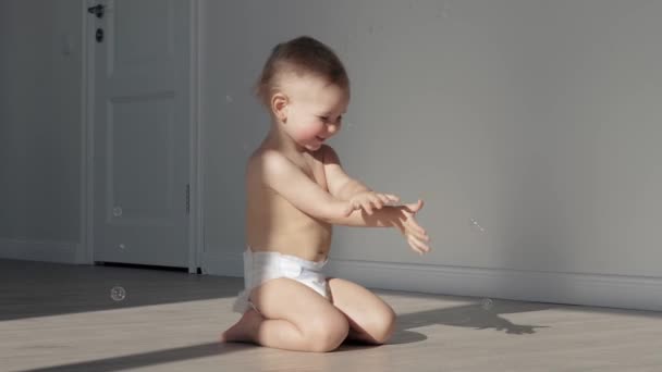 Lustiges kleines Baby spielt zu Hause mit Seifenblasen — Stockvideo